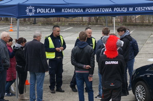 grafika-dzień, pochmurno, osoby zgromadzone przy namiocie z napisem Komenda Powiatowa Policji w Cieszynie