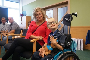 grafika-sala, dziecko na wózku inwalidzkim i mama pozują do zdjęcia