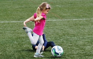 grafika-mała dziewczyna kopie w piłkę na trawniku