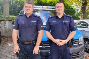 policjanci- młodszy aspirat Marek Folek i młodszy aspirant Łukasz Gruszczyk, w tle radiowóz
