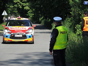 policjant obserwuje na drodze samochód rajdowy, dzień, droga