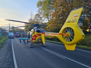 helikopter lotniczego pogotowia ratunkowego, w tle pojazdy służb ratowniczych policji i straży pożarnej, dzień, jezdnia