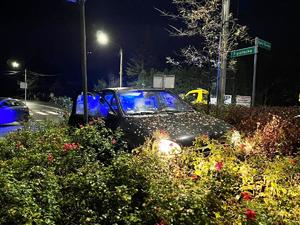 grafika-noc, samochód stoi na zieleńcu na rondzie, obok policyjny radiowóz