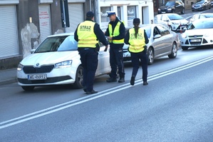 dzień, słonecznie, policjanci rozdają ulotki pieszych i kierowcom