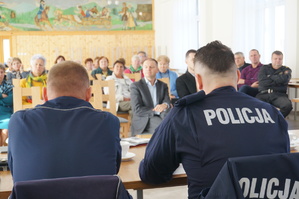 zdjęcie- uczestnicy spotkania siedzą na krzesłach w sali, jasno, policjanci siedzą naprzeciwko, policjant przemawia