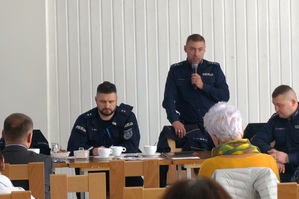 zdjęcie- uczestnicy spotkania siedzą na krzesłach w sali, jasno, policjanci siedzą naprzeciwko, policjant przemawia