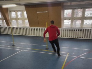 sala gimnastyczna, mężczyzna biegnie pomiędzy pachołkami