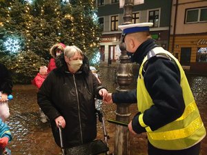 zdjęcie, ciemno, teren miasta, świąteczne dekoracje , policjant wręcza odlask