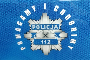 napis policja, pomagamy i chronimy, rozeta policyjna na niebieskim tle