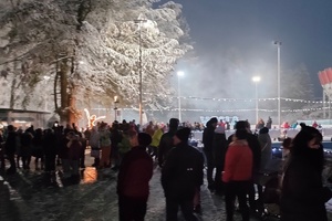 noc, zima, ludzie oglądają atrakcje świetlne widoczne na drugim planie