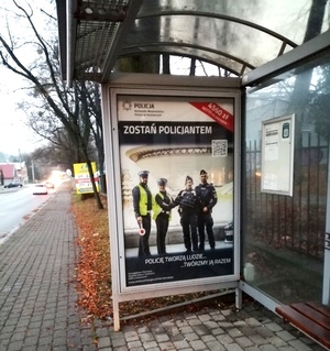 grafika- przystanek autobusowy, plakat z policjantami, dzień,