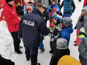 zdjęcie-zima, śnieg, dzień, policjanci w mundurach oraz osoby na stoku narciarskim