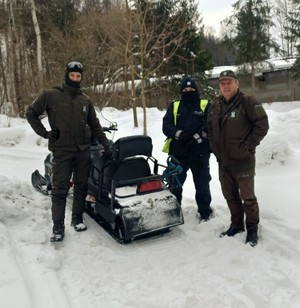 zdjęcie-dzień, śnieg, skuter śnieżny, policjant oraz strażnicy leśni