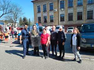 zdjęcie- słońce, parking, pojazdy służb, osoby pozują do zdjęcia