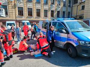 zdjęcie- słońce, parking, pojazdy służb, osoby pozują do zdjęcia