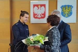 zdjęcie-sama, policjant, osoby gratulują wyróżnionemu i wręczają nagrody