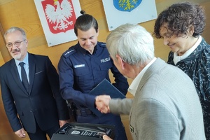 zdjęcie-sama, policjant, osoby gratulują wyróżnionemu i wręczają nagrody