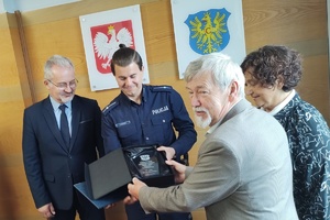 zdjęcie-sama, policjant, osoby gratulują wyróżnionemu i wręczają nagrody