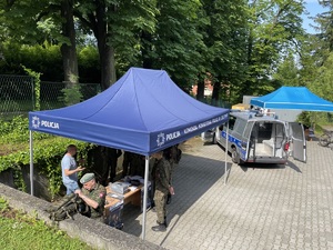 zdjęcie-młodzież zgromadzona na placu przed budynkiem komendy, radiowóz, namiot, słoneczna pogoda