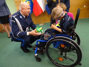 zdjęcie - komendant powiatowy otrzymuje gratulacje i podziękowania od chłopczyka na wózku inwalidzkim