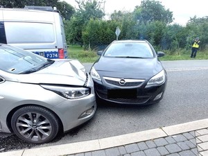 rozbite pojazdy w tle policjant wykonujący zdjęcia