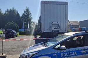 dzień, słońce, samochód policji, za nim przyczepa tira