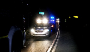 zdjęcie-noc, droga, pojazd policji z włączonymi światłami urzywilejowania