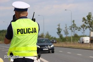 policjant na drodze, obserwuje ruch pojazdów, dzień, słonecznie