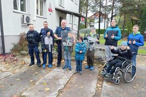 zdjęcie grupowe uczestników wycieczki, policjanci i dzieci pozują do zdjecia