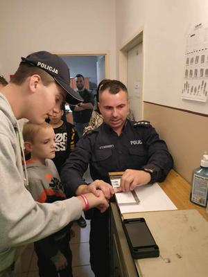 pomieszczenie, policjant pobiera odbitki palców od dzieci