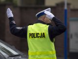 policjant w odblaskowej kamizelce ma uniesione dłonie, kieruje ruchem