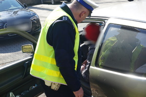 policjant kontroluje kierowcę, dzień ,kierowca siedzi w samochodzie