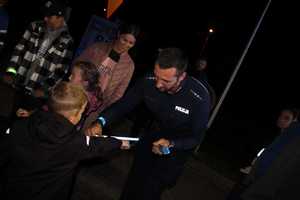 policjanci i burmistrz wręczają odblaski, noc, oświetlenie sztuczne