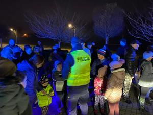 zdjęcie-noc, policjanci rozdają odblaski uczestnikom spotkania