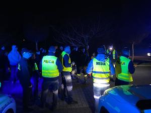 zdjęcie-noc, policjanci rozdają odblaski uczestnikom spotkania