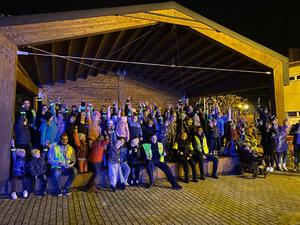 zdjęcie- noc, grupa kilkudziesięciu ludzi pozuje do zdjęcia z odblaskami w ręce
