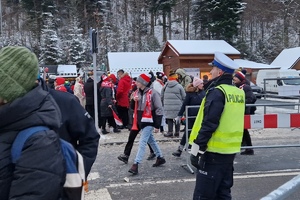 zdjęcie-zima, śnieg, droga, policjant kieruje ruchem, w tle skocznia narciarska