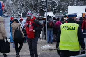 zdjęcie-zima, śnieg, droga, policjant kieruje ruchem, w tle skocznia narciarska