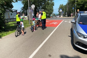 policjant kontroluje rowerzystę, wręcza mu lampki rowerowe, dzień ,słonecznie
