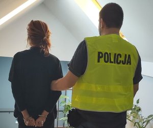 zatrzymana z zapiętymi kajdankami z policjantem tyłem do kadru