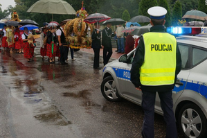 ludzie idący w korowodzie i policjant wraz z radiowozem