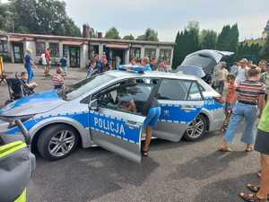 zdjęcie- dzień, plac , policyjny radiowóz, dzieci i policjanci