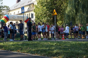 zdjęcie- dzień, słonecznie, dzieci i policjanci ćwiczą wspólnie jazdę na hulajnodze w miasteczku ruchu