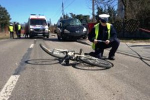 zdjecie-policjant klęczy na jezdni przy rowerze, pisze coś w notatniku