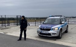 policjantka przy radiowozie, w tle zbiornik wodny