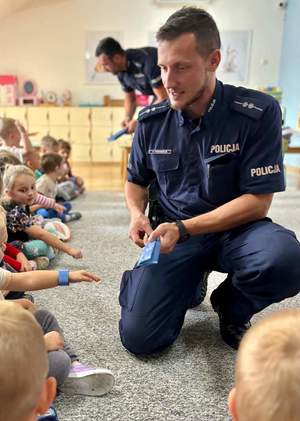 zdjęcie w sali przedszkola, policjant bawi się z dziecmi