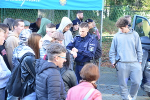 zdjęcie-plac, dzień, młodzież przygląda się i słucha co mówią i pokazują policjanci