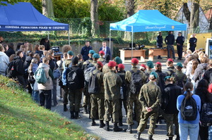 zdjęcie-plac, dzień, młodzież przygląda się i słucha co mówią i pokazują policjanci