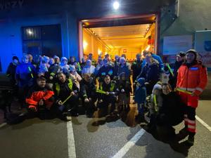 zdjęcie- noc, policjanci wręczają odblaski, ludzie pozują do zdjęć