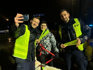 zdjęcie- noc, policjanci wręczają odblaski, ludzie pozują do zdjęć